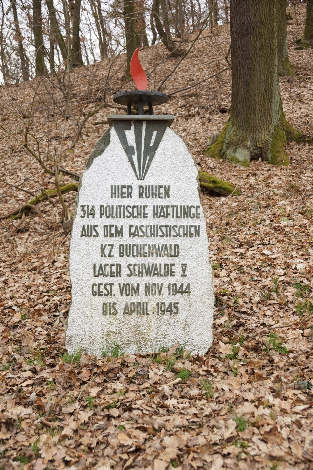 Gedenkstein, der 1955 aufgestellt wurde und sich am Eingang des Friedhofes befindet, 2022. Der Text verschweigt, dass die meisten Opfer als Juden verfolgt wurden und beziffert die Zahl der Toten fälschlicherweise mit 314. Foto: Katharina Brand