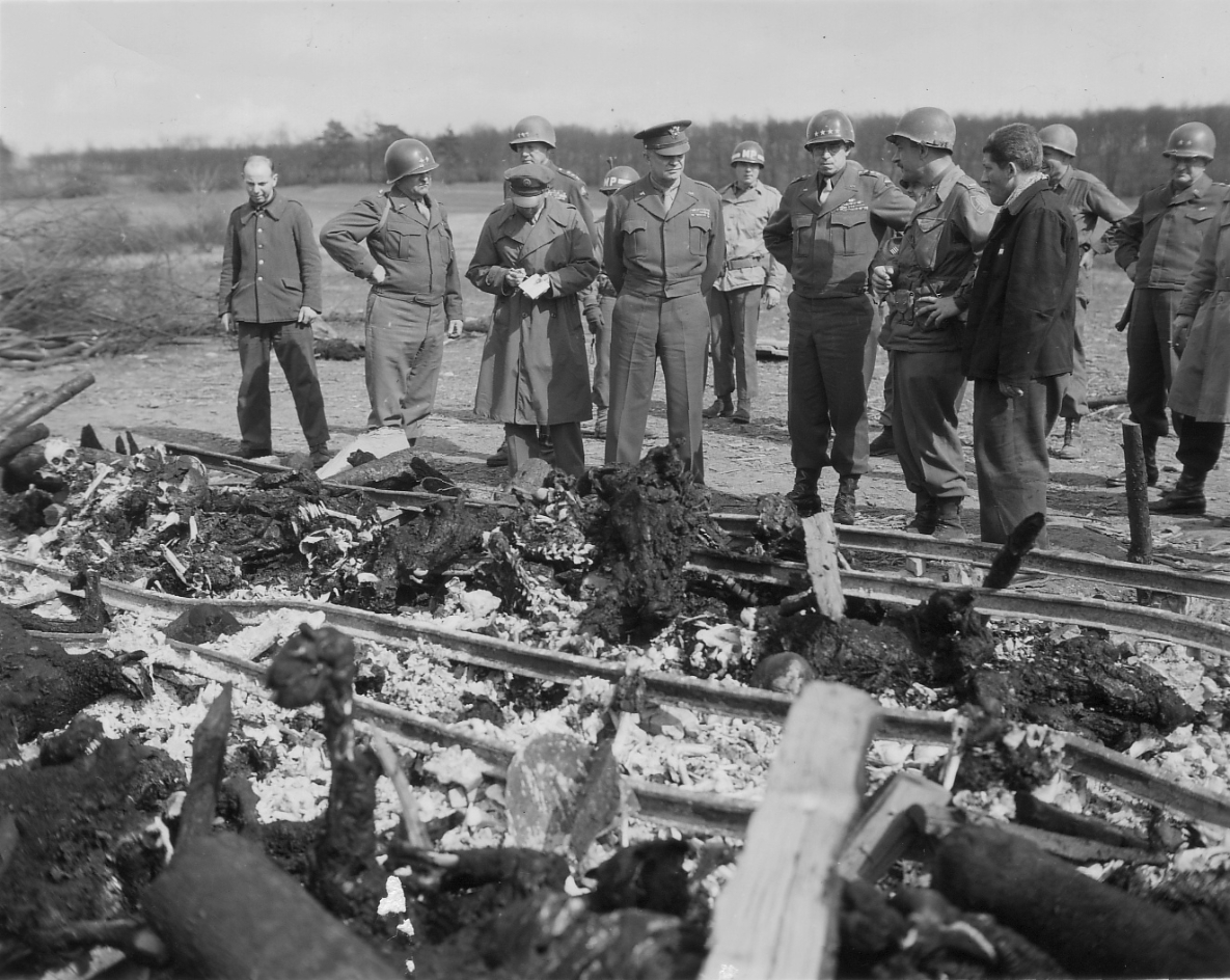 Der Überlebende Ignaz Feldmann (vorne, rechts) zeigt Generälen der U.S. Army und dem Oberbefehlshaber der alliierten Streitkräfte in Europa, Dwight D. Eisenhower (5. v. l.), Schienen, auf denen die SS Leichen verbrennen ließ. Foto: Leo Moore (U.S. Army Signal Corps)