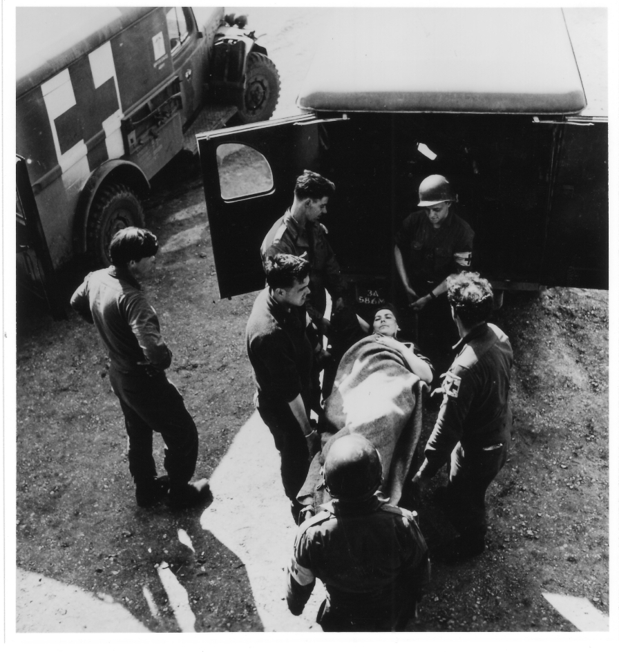 Eine Überlebende wird von Sanitätern zu einem der Krankenwagen getragen, 17. April 1945. Foto: David E. Scherman