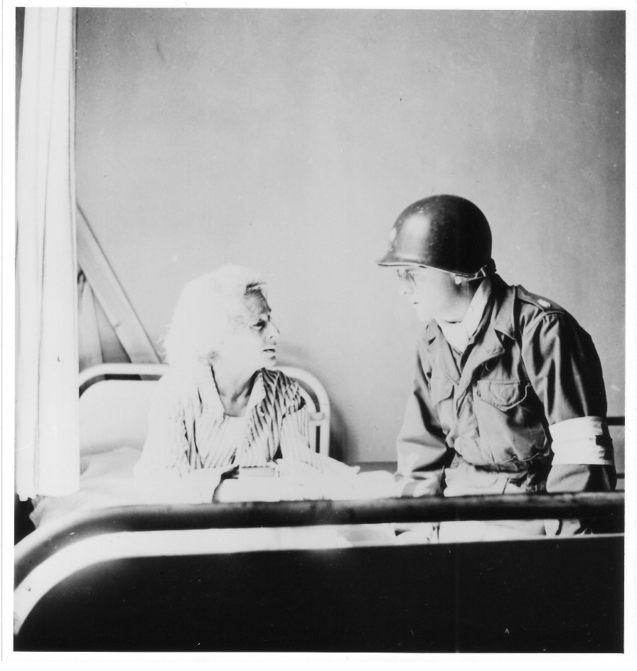 Eine Überlebende in einem Krankenbett im Lazarett in Altenburg im Gespräch mit Lieutenant Colonel J. W. Branch, Sanitätsoffizier der 6. Panzerdivision der Dritten U.S. Army, 17. April 1945. Foto: David E. Scherman