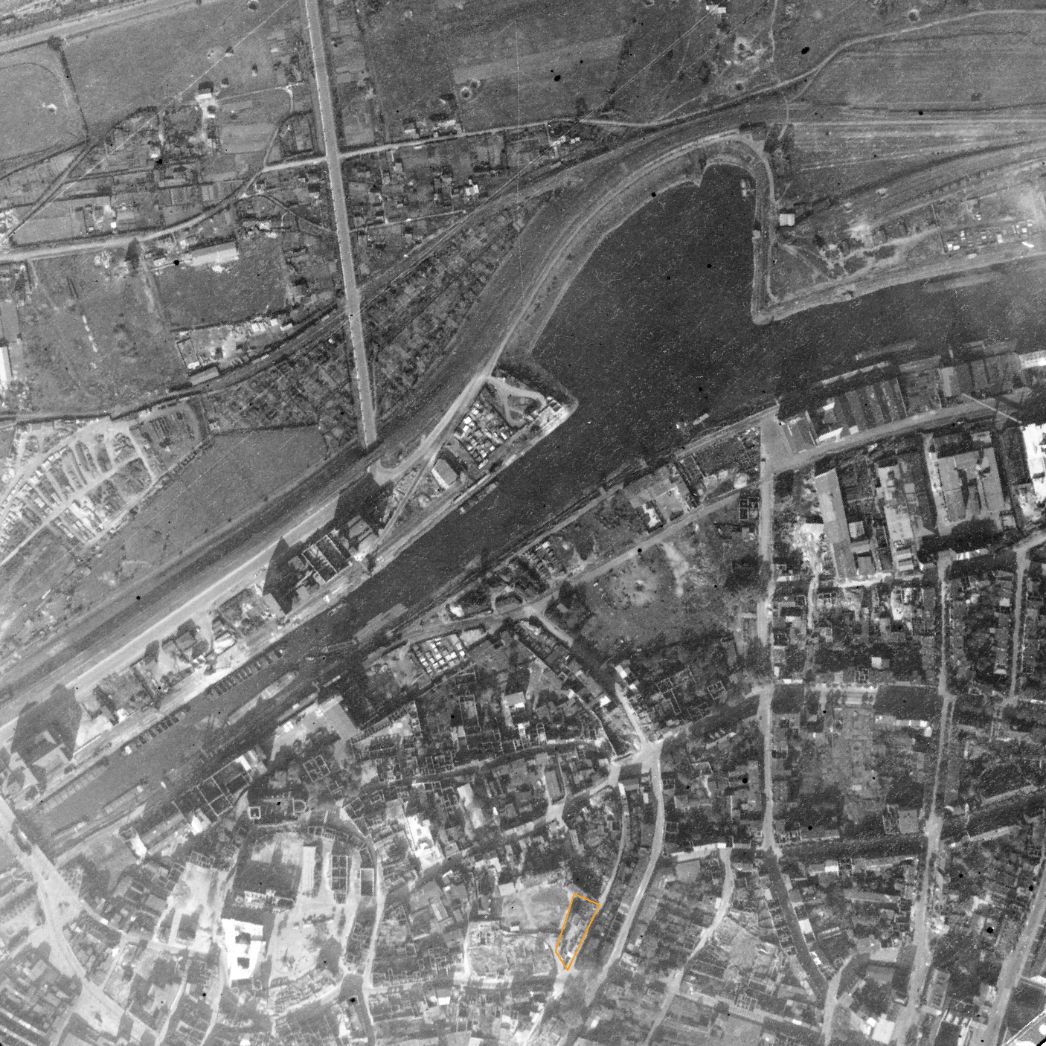 Der Duisburger Hafen (oben) und Teile der Innenstadt. Aufnahme der alliierten Luftaufklärung, 9. Oktober 1943 (Ausschnitt). Markiert ist der Bereich, in dem sich ab Mai 1943 die Häftlingsunterkunft in der ehemaligen Diakonenanstalt in der Obermauerstraße befand.