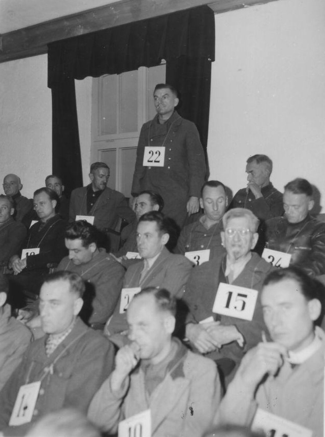 Michael Redwitz (stehend, Nr. 22) als Angeklagter beim Prozess in Dachau gegen Verantwortliche des KZ Dachau, 17. November 1945
