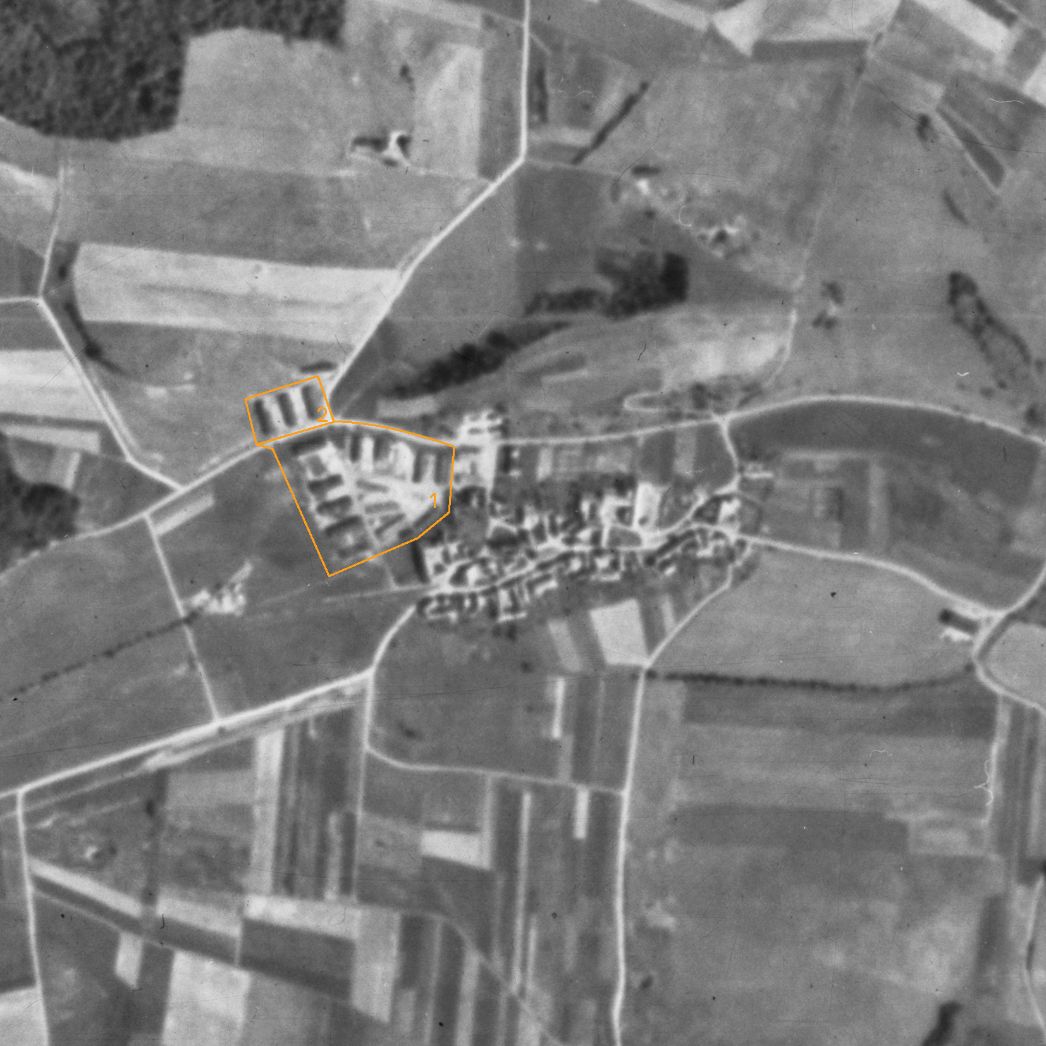 Die Ortschaft Harzungen. Aufnahme der alliierten Luftaufklärung, 22. Juli 1945 (Ausschnitt). Markiert ist das ehemalige Lagergelände am westlichen Ortsrand: das Barackenlager für die KZ-Häftlinge (1) und die Unterkünfte für die Wachmannschaft (2).