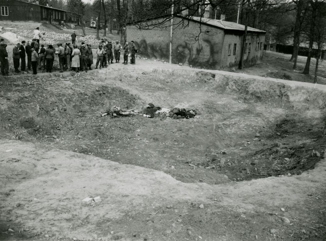 Befreite Häftlinge und Angehörige der U.S. Army an einem der Massengräber am Lager, Mitte April 1945. Foto: Preston A. Reed (U.S. Army Signal Corps)