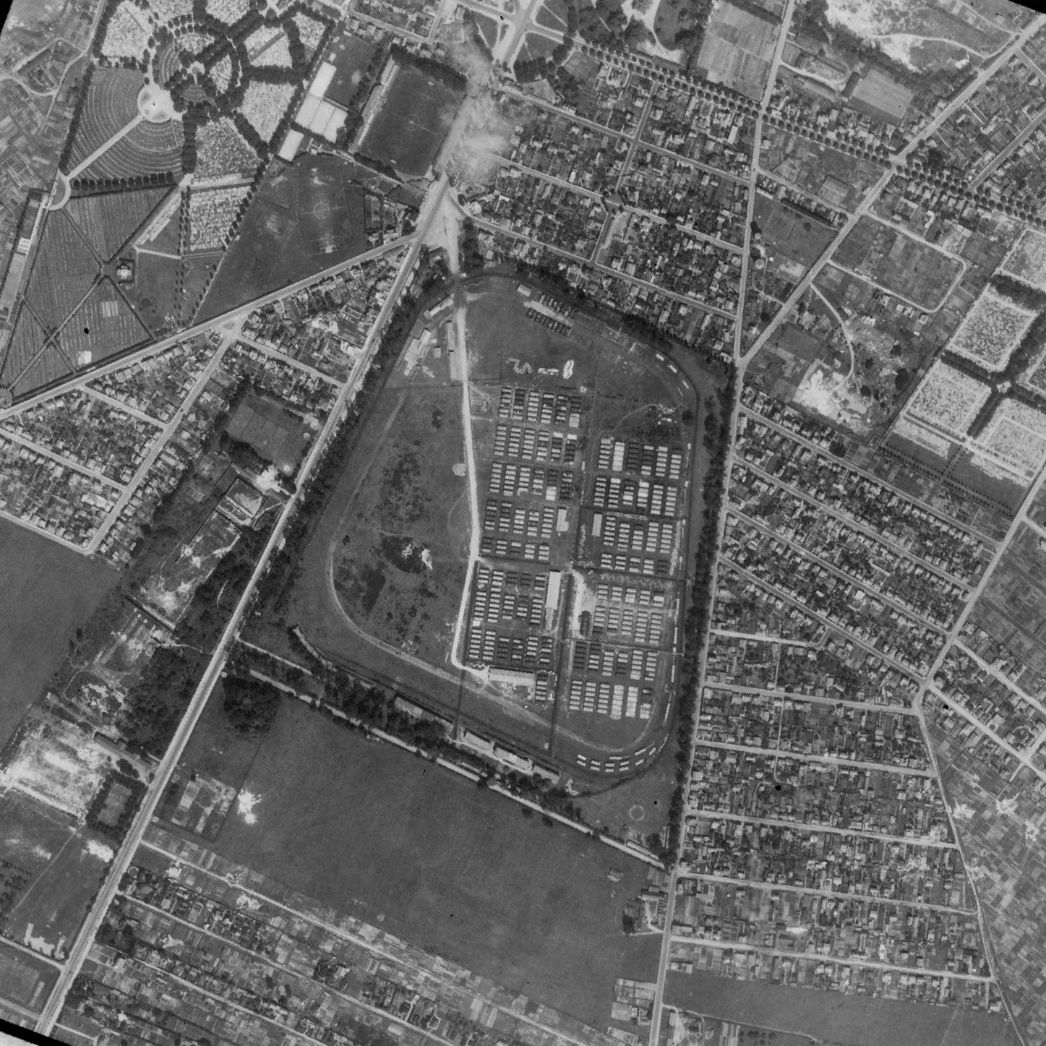 Nördlicher Stadtteil von Saint-Étienne-du-Rouvray südlich angrenzend an Rouen. Aufnahme der alliierten Luftaufklärung, 3. August 1944. Die Pferderennbahn, l‘hippodrome des Bruyères befindet sich in der Bildmitte. Darin zu erkennen ist das Lager aus Wellblechbaracken in denen die Häftlinge untergebracht waren.