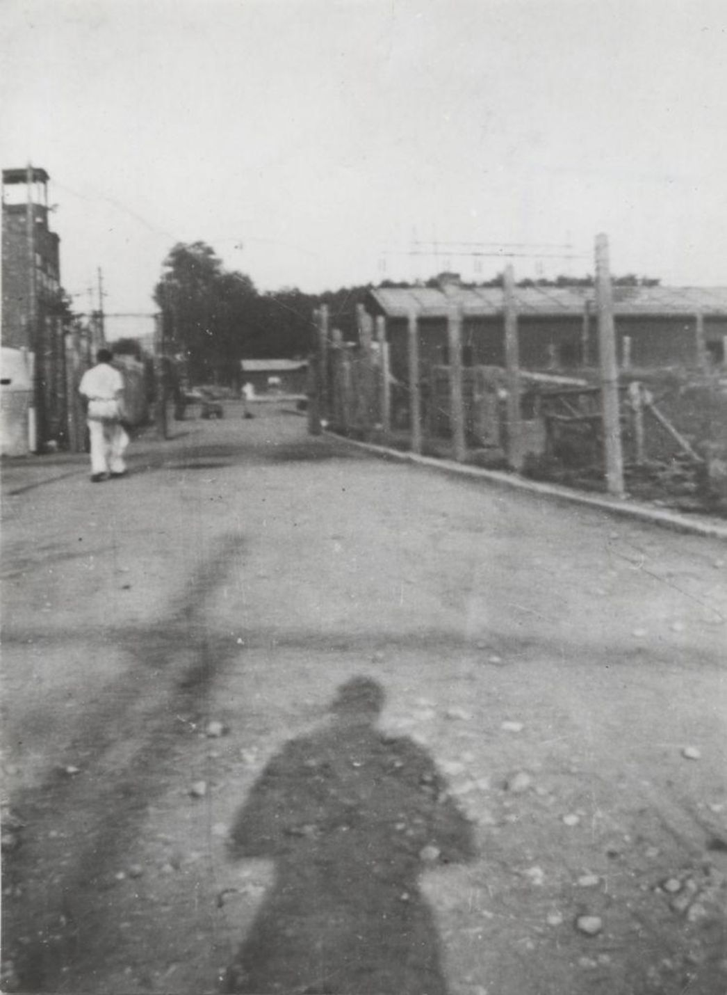 Der Eingangsbereich des Lagers am Veckenstedter Weg 23, Sommer 1944. Der damalige Lagerälteste, der deutsche Häftling Hugo Launicke, machte die illegale Aufnahme. Rechts hinter dem Zaun ist die Küchenbaracke zu sehen.